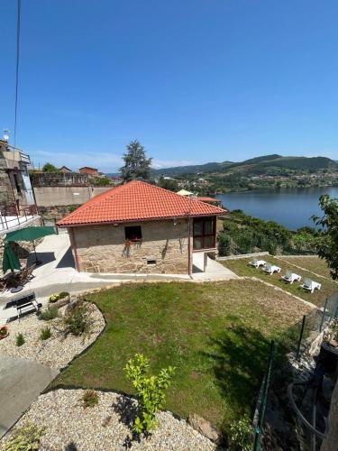 a building with a red roof with a view of a lake at Casa da Ramona in Ribadavia