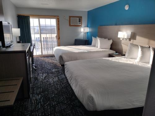 a hotel room with two beds and a television at Baymont by Wyndham Duluth Spirit Mountain in Duluth