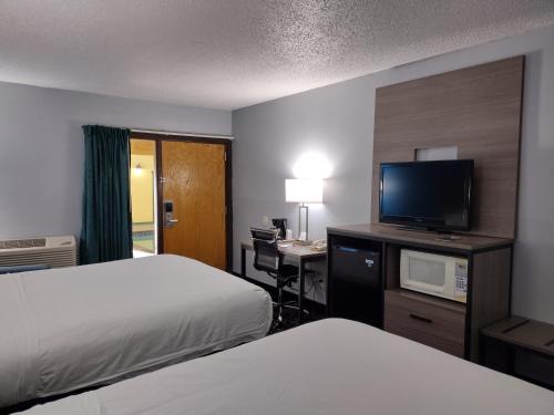a hotel room with two beds and a desk with a tv at Baymont by Wyndham Duluth Spirit Mountain in Duluth