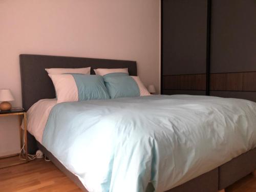 Elle comprend un grand lit avec des draps blancs et des oreillers bleus. dans l'établissement Villa Angélina, à Saint-Cyr-lʼÉcole