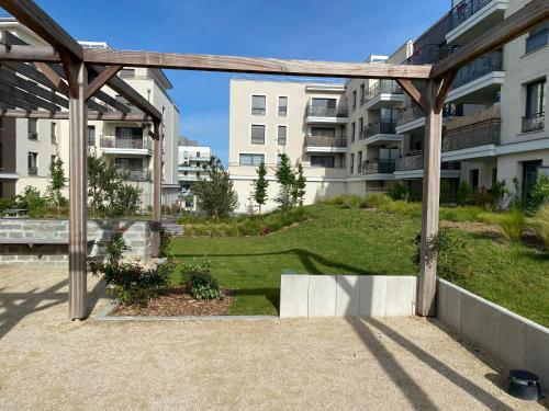une pergola en bois devant un bâtiment dans l'établissement Villa Angélina, à Saint-Cyr-lʼÉcole
