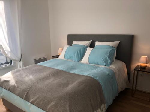 une chambre avec un lit avec des oreillers bleus et blancs dans l'établissement Villa Angélina, à Saint-Cyr-lʼÉcole