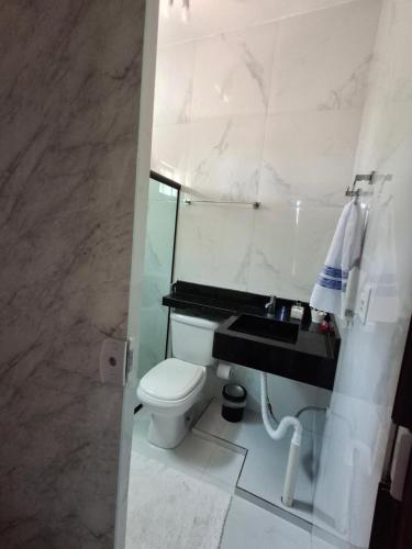 a white bathroom with a toilet and a sink at Casa da praia in Tutóia