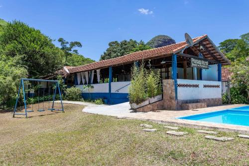 a house with a pool and a basketball hoop at Pousada Pedra de Paraibuna in Comendador Levy Gasparian