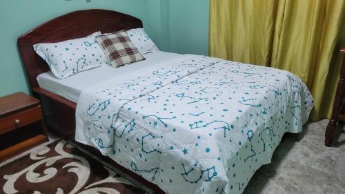 a bed with a blue and white comforter at Carolina Lodging Apartment - Free & Fast Wi-Fi in Douala