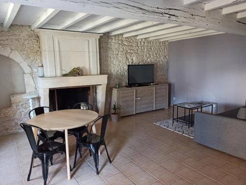 un salon avec une table et une télévision dans l'établissement La Picoulade, à Saint-Hilaire-du-Bois