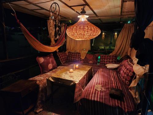 a room with a couch and a table and a chandelier at Quadra Sphere rooftop in Tamraght Ouzdar