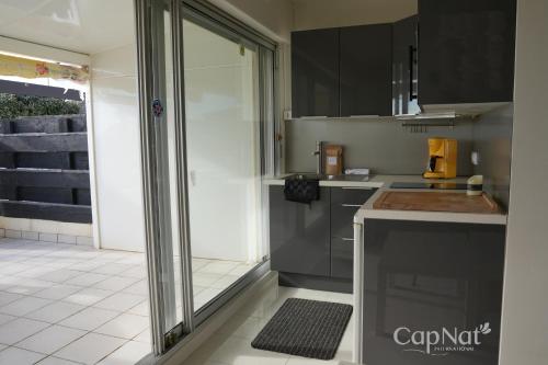 une cuisine avec des armoires noires et une porte coulissante en verre dans l'établissement CapNat - Village Naturiste - Port Nature - Villa Pamela, au Cap d'Agde