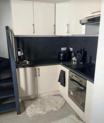 une cuisine avec des armoires blanches et un comptoir noir dans l'établissement Strasbourg centre proche gare, à Strasbourg