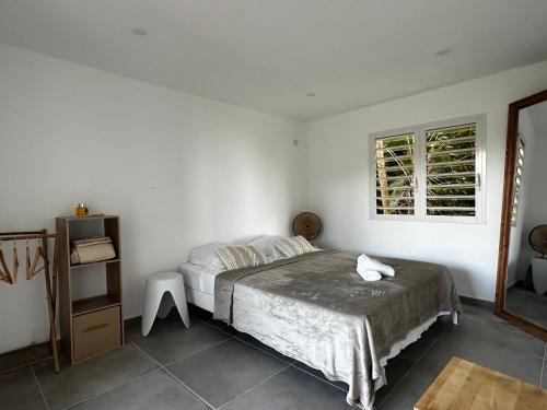a white bedroom with a bed and a window at L'O - Au cœur de la Grande-Terre - T2 in Morne-à-lʼEau