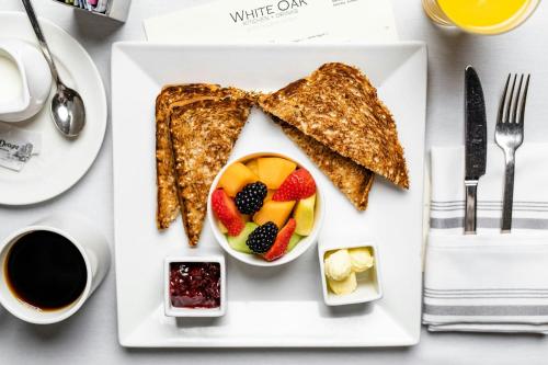 a white plate with toast and fruit on it at The Westin Oaks Houston at the Galleria in Houston