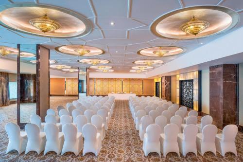 a conference room with rows of white chairs and a stage at The St. Regis Mumbai in Mumbai