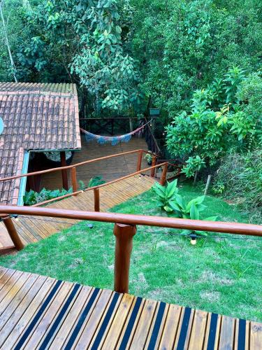 a wooden deck with a hammock in a garden at Chalé nas Árvores in São Francisco Xavier
