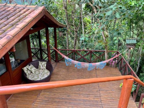 a wooden porch with a hammock on a deck at Chalé nas Árvores in São Francisco Xavier
