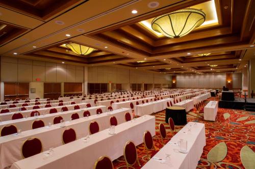 a large banquet hall with white tables and chairs at Tulsa Marriott Southern Hills in Tulsa