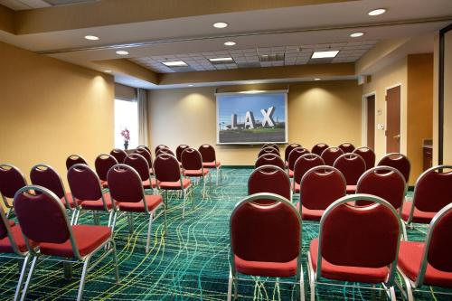 a conference room with red chairs and a screen at SpringHill Suites Los Angeles LAX/Manhattan Beach in Hawthorne