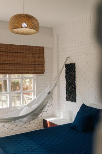 a hammock in a bedroom with a bed and a tub at Palawan Pousada & Bistrô in Nísia Floresta