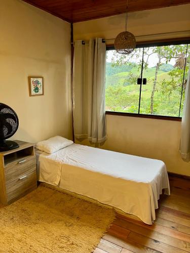a bedroom with a bed and a window at Chalé nas Árvores in São Francisco Xavier