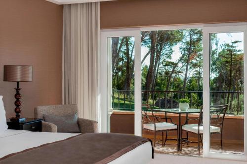a bedroom with a bed and a balcony with a table and chairs at Penha Longa Resort in Sintra