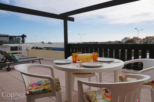 une table blanche et des chaises sur un balcon avec vue dans l'établissement CapNat - Village Naturiste - Port Nature - Villa Malibu, au Cap d'Agde