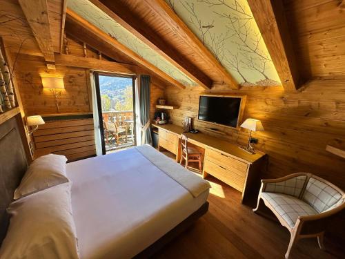 a bedroom with a bed and a desk and a television at Gran Baita Hotel & Wellness in Courmayeur