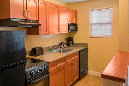 a kitchen with wooden cabinets and a sink and a stove at TownePlace Suites by Marriott Boulder Broomfield/Interlocken in Broomfield