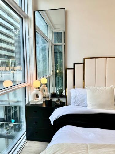 a bedroom with two beds and a large window at Toronto Downtown Core Condo 2 BED 2 BATH in Toronto