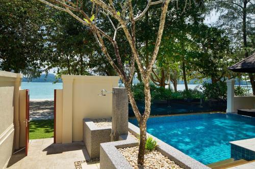 a swimming pool with a tree next to a house at The Westin Langkawi Resort & Spa in Kuah