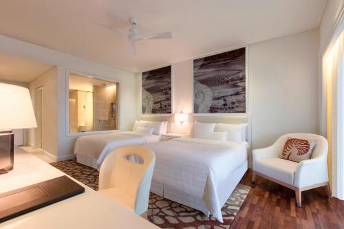 a hotel room with two beds and a chair at The Westin Langkawi Resort & Spa in Kuah