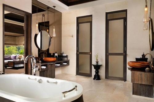 a bathroom with a bath tub and a mirror at Mandapa, a Ritz-Carlton Reserve in Ubud
