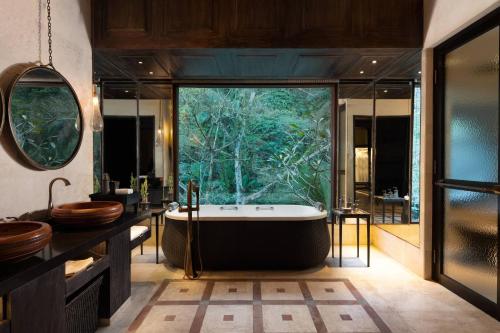 a bathroom with a tub and a large window at Mandapa, a Ritz-Carlton Reserve in Ubud