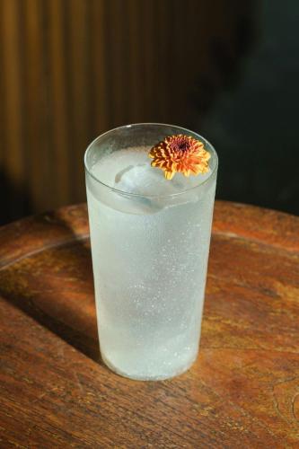 a glass of water with a flower in it on a table at Mandapa, a Ritz-Carlton Reserve in Ubud