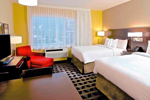 a hotel room with two beds and a red chair at TownePlace Suites by Marriott Anchorage Midtown in Anchorage