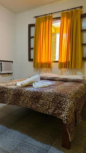 a leopard print bed in a room with a window at Pousada Pratagy in Saquarema