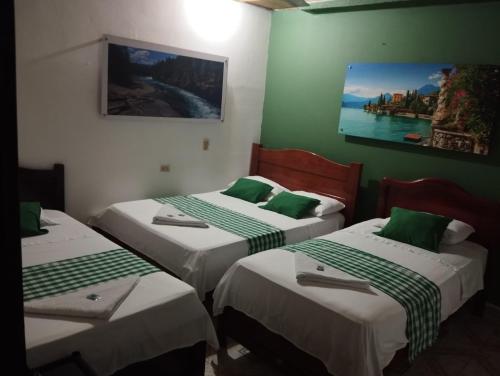 a room with three beds with green and white sheets at Hotel Sol y Mar in Curumaní