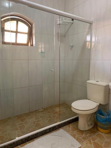 a bathroom with a toilet and a glass shower at Pousada Pratagy in Saquarema