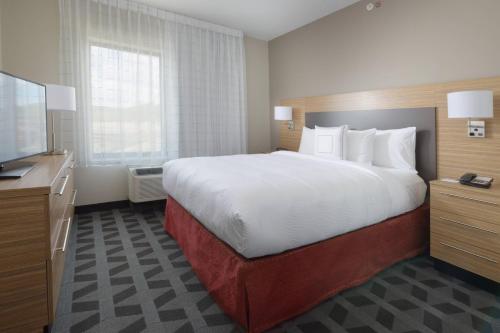 a hotel room with a large bed and a flat screen tv at TownePlace Suites by Marriott Denver South/Lone Tree in Lone Tree