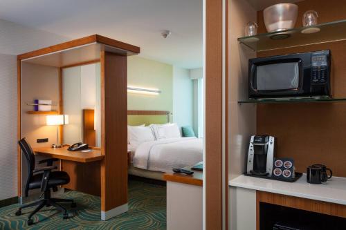 a hotel room with a bed and a desk with a television at SpringHill Suites by Marriott Kennewick Tri-Cities in Kennewick