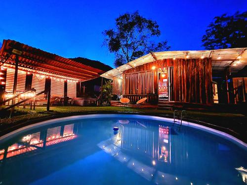 a swimming pool in front of a house at night at Posada Turistica Rural y Glamping Altos del Dorado La Mesa in La Mesa