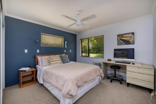 a bedroom with a bed and a desk with a television at Rangimarie - Paihia Holiday Home in Paihia