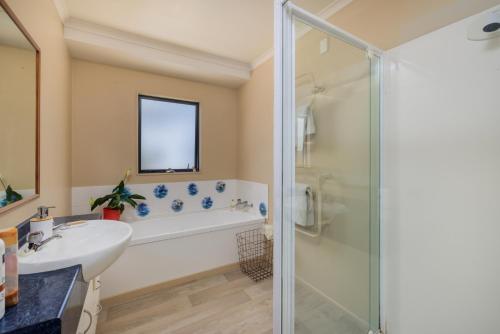 a bathroom with a tub and a sink and a shower at Rangimarie - Paihia Holiday Home in Paihia