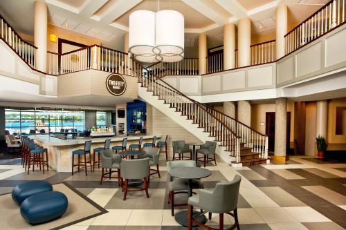 a lobby with a staircase and tables and chairs at Sheraton Portsmouth Harborside Hotel in Portsmouth