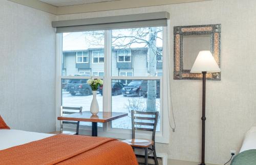 a bedroom with a window with a table and a vase with flowers at Mountainside Inn 406 by Alpine Lodging Telluride in Telluride