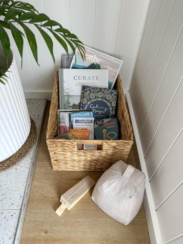 a basket filled with books on a floor next to a plant at Banjos Cabin Gippsland - Luxury Eco Stay - King Bed, Pond Valley Views, Fireplace in Seaton