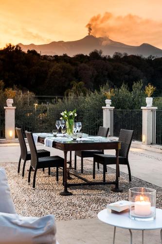 a dining table and chairs with a fire in the background at Donna Carmela Resort & Lodges in Riposto