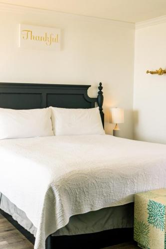a bedroom with a large white bed with a black headboard at Laguna Cove Hotel in Laguna Beach