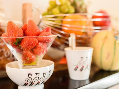 un bol de fraises sur une table avec deux tasses dans l'établissement Hotel Les Almadies - Coeur de Ville, à Saint-Jean-de-Luz