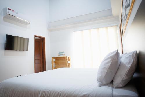 a bedroom with a white bed with pillows and a window at Hotel Agata Boutique pinares Pereira in Pereira