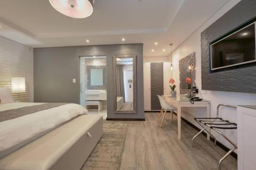 a hotel room with a bed and a desk and a bathroom at Protea Hotel by Marriott Mossel Bay in Mossel Bay