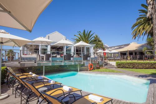 a pool with chairs and umbrellas next to a resort at Protea Hotel by Marriott Mossel Bay in Mossel Bay